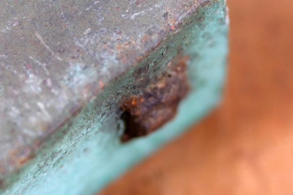 Nahaufnahme von rostigem Metall mit grünlicher Patina und braunen Verfärbungen.