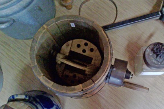 Holzkübel mit einem Holzmechanismus und Metallgriffen, umgeben von weiteren Gegenständen.